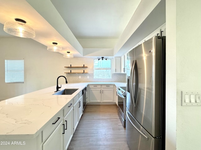 kitchen with white cabinetry, tasteful backsplash, kitchen peninsula, stainless steel fridge, and sink