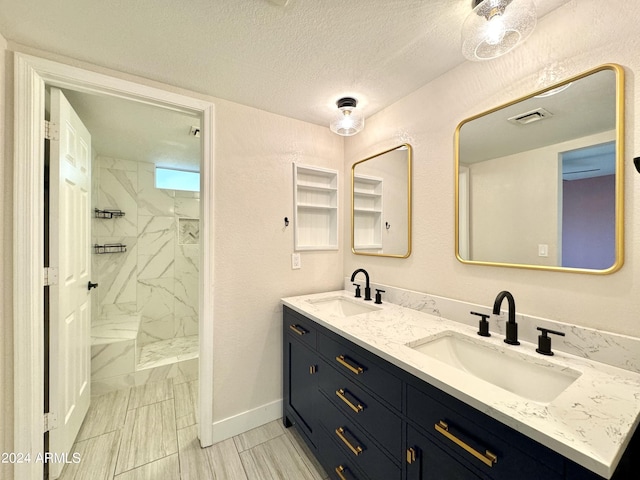 bathroom with vanity, tiled shower, and a textured ceiling