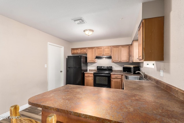 kitchen featuring kitchen peninsula, sink, black appliances, and hardwood / wood-style flooring