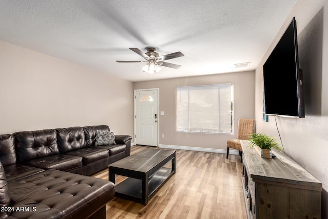 living room with ceiling fan, a textured ceiling, and light hardwood / wood-style flooring