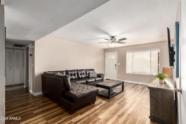 living room featuring ceiling fan, hardwood / wood-style floors, and a textured ceiling