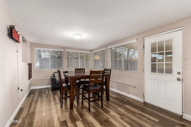 dining area with dark hardwood / wood-style flooring and brick wall