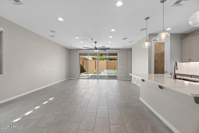 interior space with visible vents, a ceiling fan, baseboards, open floor plan, and a sink