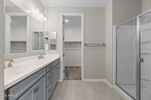 bathroom with double vanity, a sink, a walk in closet, and a stall shower