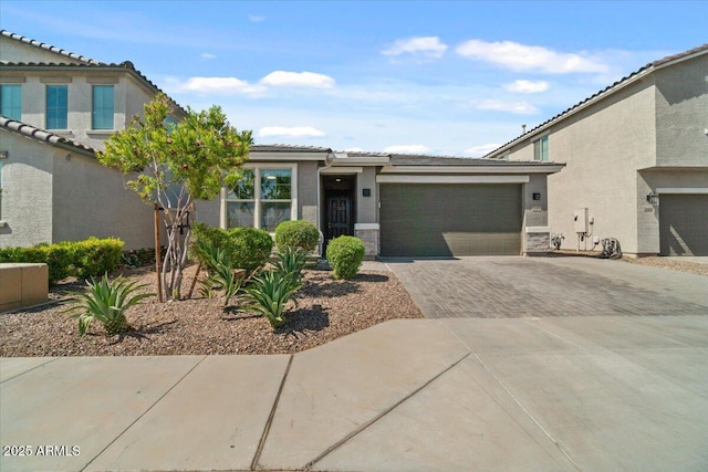 view of front facade featuring a garage, stucco siding, driveway, and a tiled roof