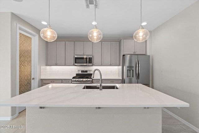 kitchen with visible vents, baseboards, gray cabinets, a sink, and stainless steel appliances
