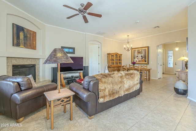 living room with a tile fireplace, visible vents, arched walkways, and ornamental molding