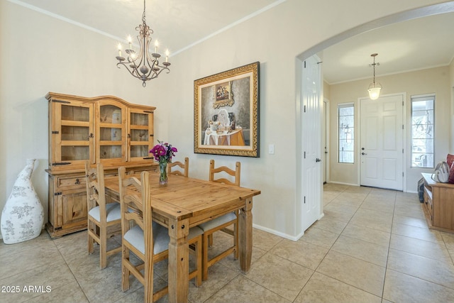 dining area featuring arched walkways, crown molding, light tile patterned floors, baseboards, and a chandelier