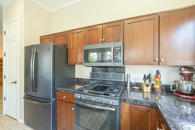 kitchen featuring tile counters, brown cabinets, appliances with stainless steel finishes, and a sink