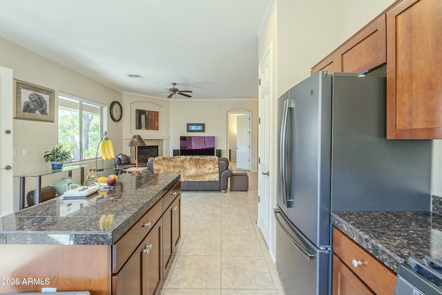 kitchen featuring visible vents, brown cabinets, dark countertops, a fireplace, and light tile patterned floors