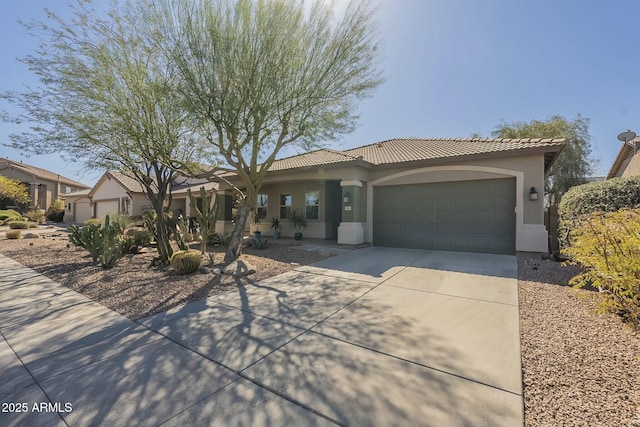 view of front of house featuring a tiled roof, an attached garage, driveway, and stucco siding