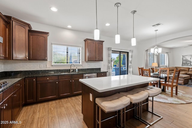 kitchen featuring decorative light fixtures, sink, a kitchen breakfast bar, and light wood-type flooring