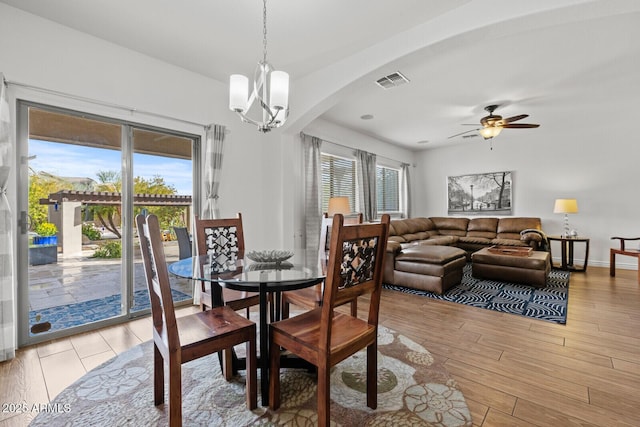 dining space with ceiling fan with notable chandelier and light hardwood / wood-style flooring