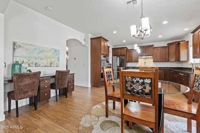 dining room featuring light wood-type flooring, sink, and a notable chandelier