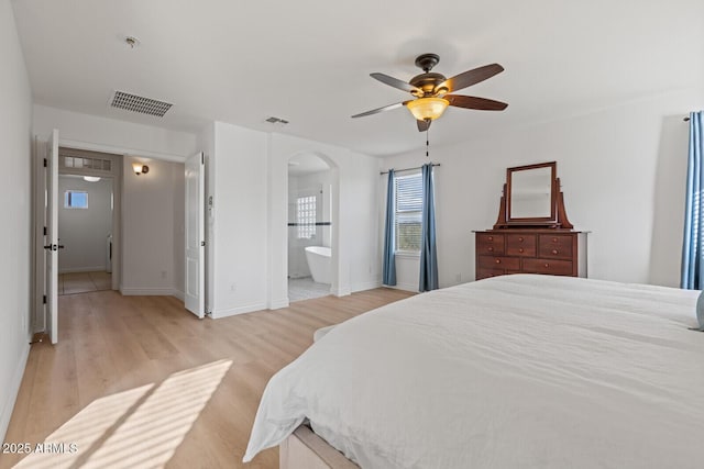 bedroom with light wood-type flooring, ceiling fan, and connected bathroom