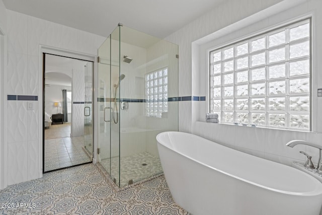 bathroom featuring separate shower and tub, tile walls, tile patterned floors, and a wealth of natural light