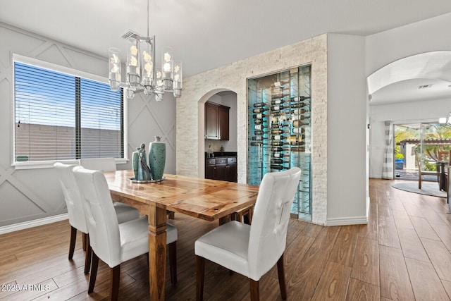 dining space featuring an inviting chandelier, a healthy amount of sunlight, and light hardwood / wood-style flooring