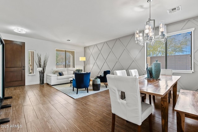 dining space with wood-type flooring and a notable chandelier