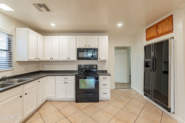 kitchen with visible vents, dark countertops, black appliances, a sink, and light tile patterned flooring