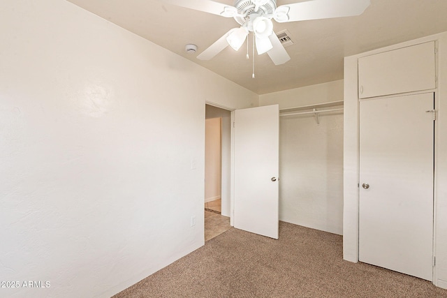 unfurnished bedroom featuring ceiling fan, a closet, visible vents, and light colored carpet