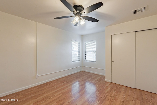 unfurnished bedroom featuring baseboards, light wood-style flooring, visible vents, and a closet