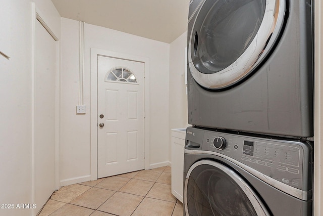 washroom with cabinet space, light tile patterned floors, baseboards, and stacked washer / dryer