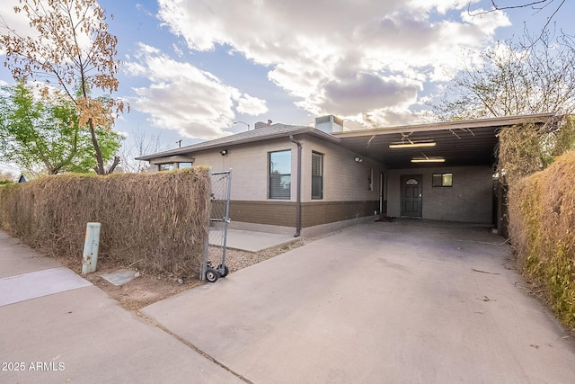 view of front facade with a carport, concrete driveway, and brick siding