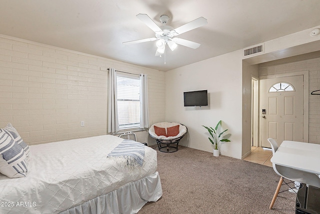 carpeted bedroom with brick wall, visible vents, and ceiling fan