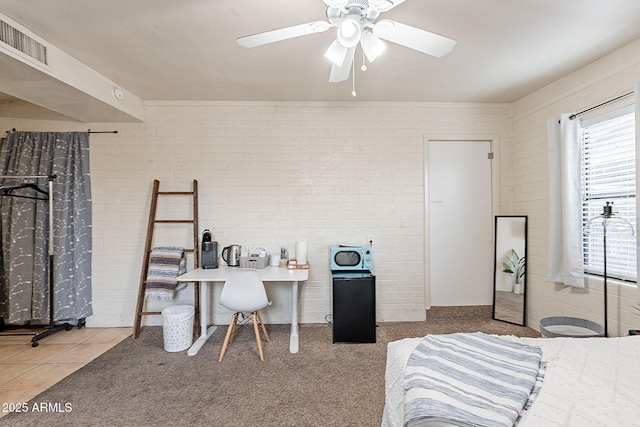 carpeted bedroom with brick wall, tile patterned flooring, visible vents, and a ceiling fan