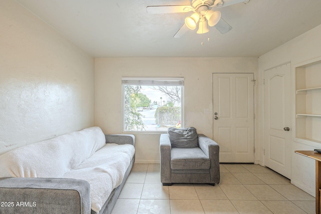 living area featuring light tile patterned floors, ceiling fan, baseboards, and built in features