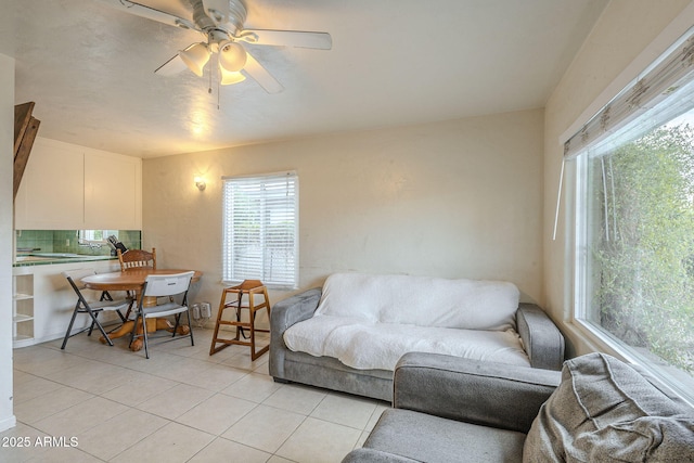 living area with a ceiling fan and light tile patterned floors