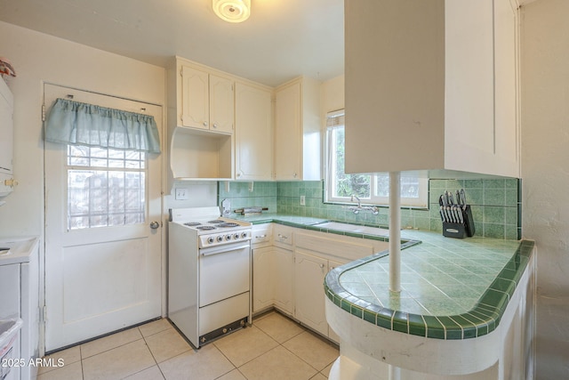 kitchen featuring tile countertops, white electric range oven, tasteful backsplash, and a sink