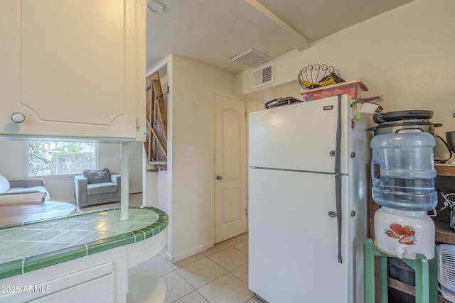 kitchen featuring freestanding refrigerator, visible vents, tile countertops, and light tile patterned flooring