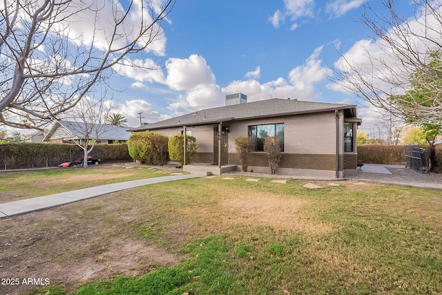 view of front of house featuring brick siding, fence, and a front lawn