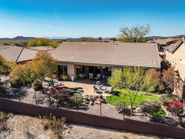 back of house with a fenced backyard, a tile roof, a patio area, a mountain view, and stucco siding