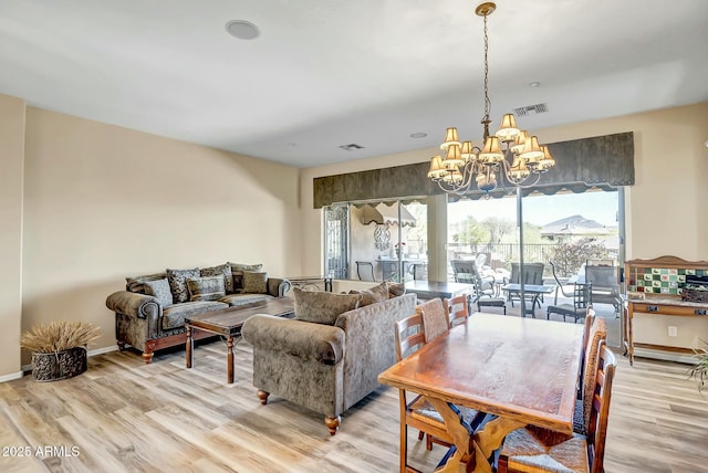 living room with baseboards, light wood-style flooring, visible vents, and a notable chandelier