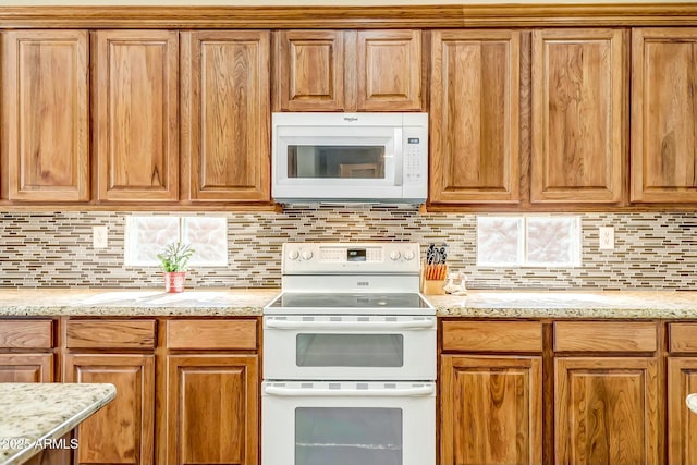 kitchen featuring light stone counters, white appliances, brown cabinets, and backsplash