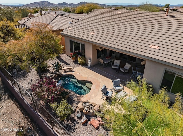 rear view of house featuring a tile roof, a patio, stucco siding, fence, and a mountain view