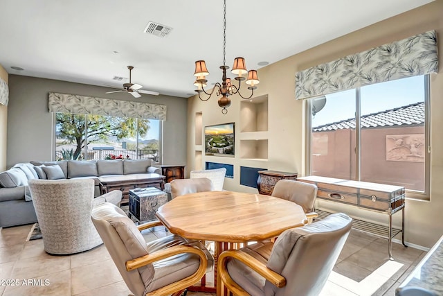 dining space featuring light tile patterned floors, ceiling fan with notable chandelier, visible vents, baseboards, and built in features