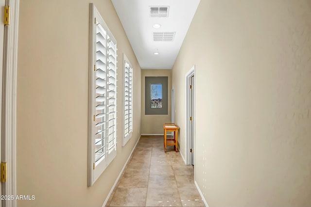 hall with visible vents, baseboards, and light tile patterned flooring
