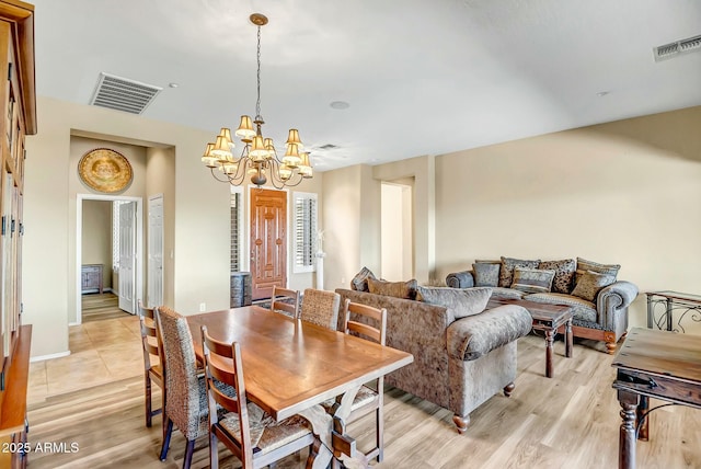 dining area with visible vents, light wood-style flooring, and an inviting chandelier