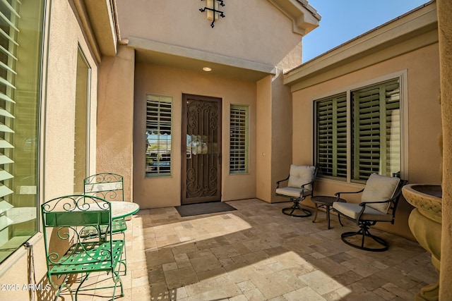 view of exterior entry featuring a patio area and stucco siding