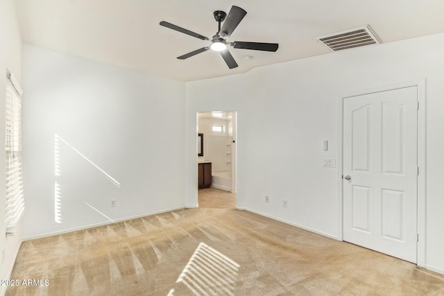 unfurnished bedroom featuring baseboards, visible vents, ensuite bathroom, and light colored carpet