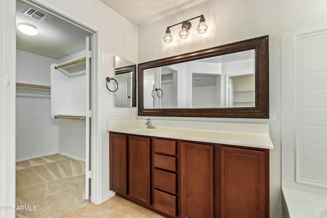 bathroom with a spacious closet, tile patterned flooring, vanity, and visible vents