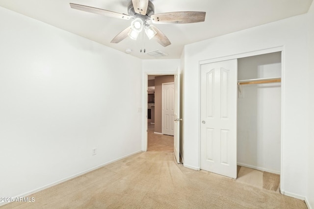 unfurnished bedroom with light carpet, ceiling fan, a closet, and baseboards