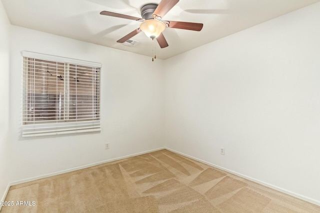 carpeted spare room featuring a ceiling fan, visible vents, and baseboards