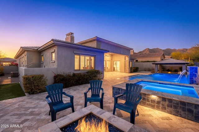 back of property featuring an outdoor fire pit, a fenced in pool, a patio, a chimney, and a gazebo