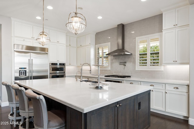 kitchen featuring stainless steel appliances, backsplash, white cabinets, and wall chimney range hood