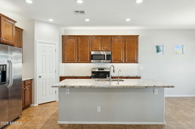 kitchen with stainless steel appliances, visible vents, a sink, and light stone counters