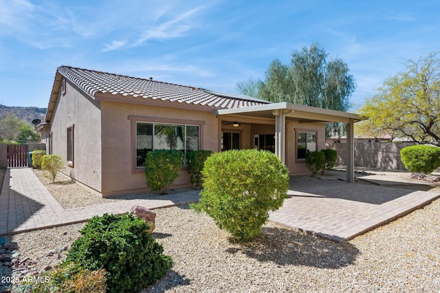 back of house with ceiling fan, a tile roof, fence, a patio area, and stucco siding